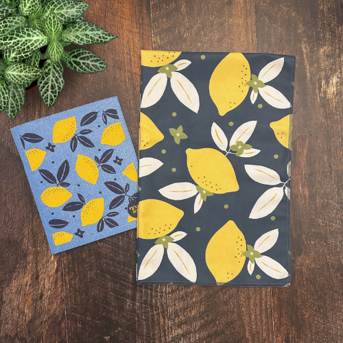 Duo pour la cuisine avec un chiffon suédois et un linge à vaisselle en microfibre avec des citrons  sur une planche de bois. 