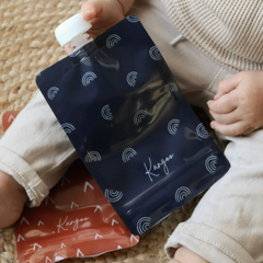 Pochette à boire réutilisable de couleur marine tenue par un enfant assis sur le sol. 