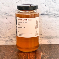 Un pot de miel d'été des Miels d'Anicet du Québec déposé sur un eplanche de bois.  Un miel classtique de grande qualité pour 340 grammes. 