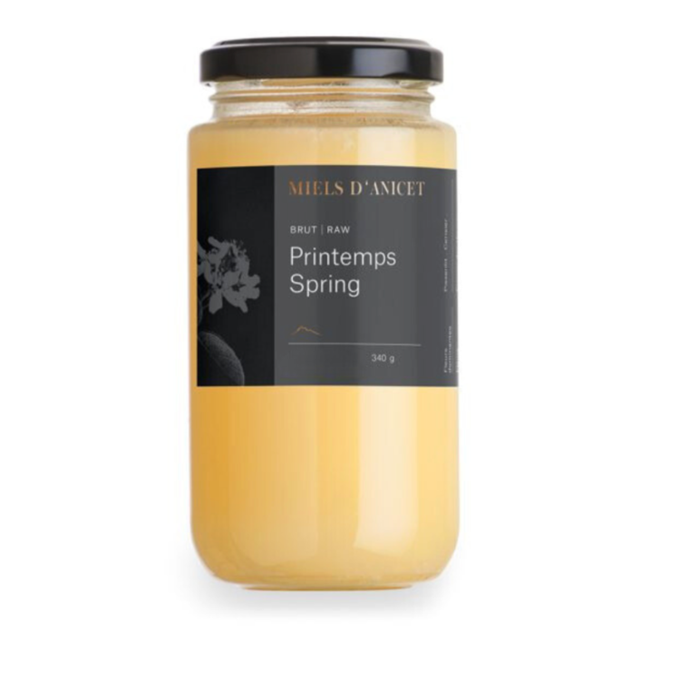 Pot de miel bruc des Miels d'Anicet avec une étiquette noire et un couvercle noir, sur fond blanc. 