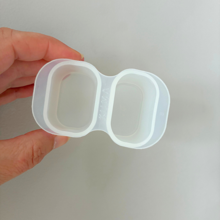 Moule en silicone blanc sur lequel on peut lire KIIMA tenu dans une main et un fond gris.