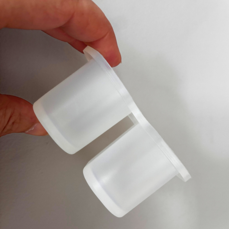 Moule double en silicone blanc tenu dans une main avec un fond gris. 