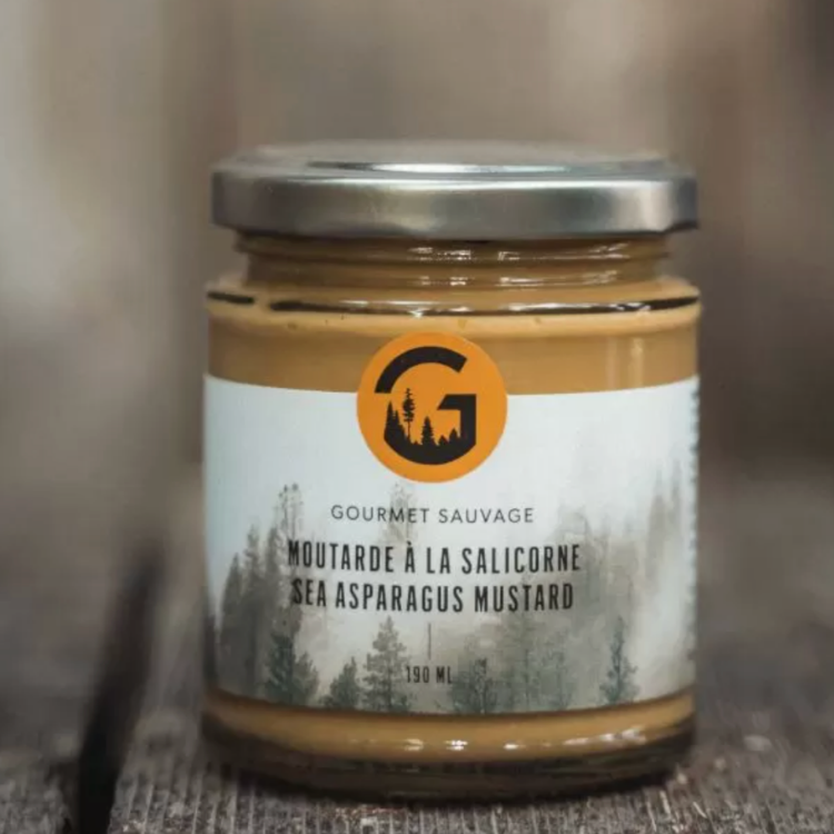 Pot avec l'inscription Moutarde  la Salicorne de Gourmet sauvage déposé sur une planche en bois foncé et un fond flou. 