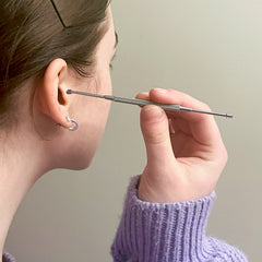 Jeune femme qui tient un oriculi dans son oreille et qui effectue un nettoyage