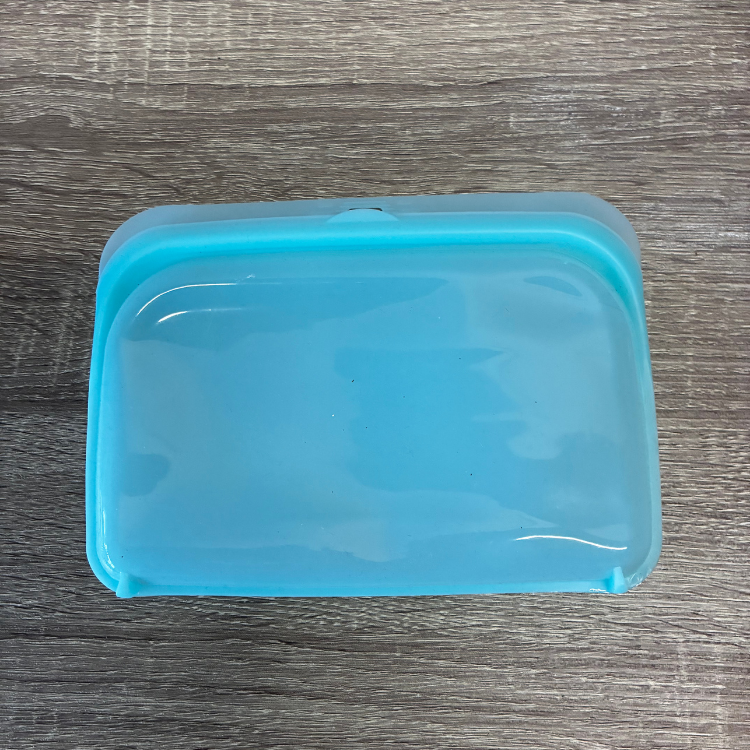 Un petit sac en silicone bleu déposé sur une planche en bois. 