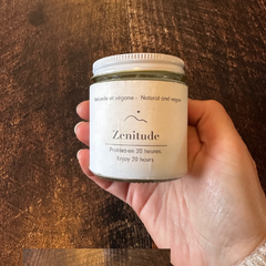 Bougie zenitude tenue dans une main sur un planche de bois