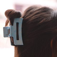 Pince à cheveux bleue en plastique recyclé de Unique plastique attaché sur des cheveux longs bruns. 