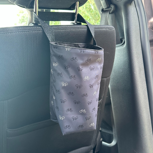 Poubelle de voiture grise avec des motif de vélos accroché sur l'appui tête