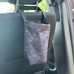 Poubelle de voiture grise avec des motif de vélos accroché sur l'appui tête