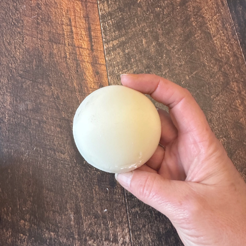 Revitalisant en barre tenu dans une main au dessus d'une planche de bois