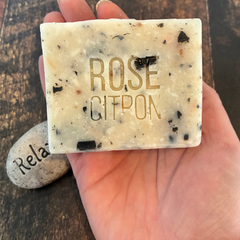 Savon Rose citron fabriqué avec des savons récupéré tenu dans une main au-dessus d'une planche en bois. 