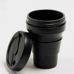 tasse café réutilisable Stojo rétractable en silicone de couleur noire et son couvercle  sur fond blanc