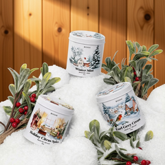 3 boitiers en métal blanc sur lesquelles il est inscrit Bisou Winter Mint, Earl. grey cream, Holiday citrus spice déposé sur de la neige avec des plante et un arrière fond de neige. 