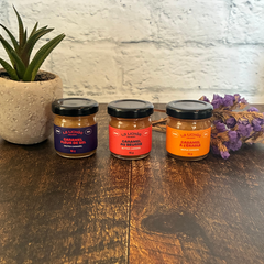 Trois petits pots de caramels un à côté de l'autre de l'entreprise québécoise La lichée (caramel salé, caramel à l'érable et caramel au beurre) à côté d'une plante et de fleurs. 