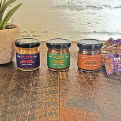 Trois petits pots de caramels un à côté de l'autre de l'entreprise québécoise La lichée (caramel salé, caramel au chocolat et caramel au café) à côté d'une plante et de fleurs. 