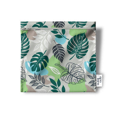 Un sac réutilisable en tissu pour les collations, sandwich, noix, biscuits, crudités, de couleur beige avec des feuilles tropicales vertes et blanche ainsi que des formes arrondis de couleur bleue pâle, beige et verte. Le sac est à plat sur un fond blanc et porte l'étiquette de Eco Loco