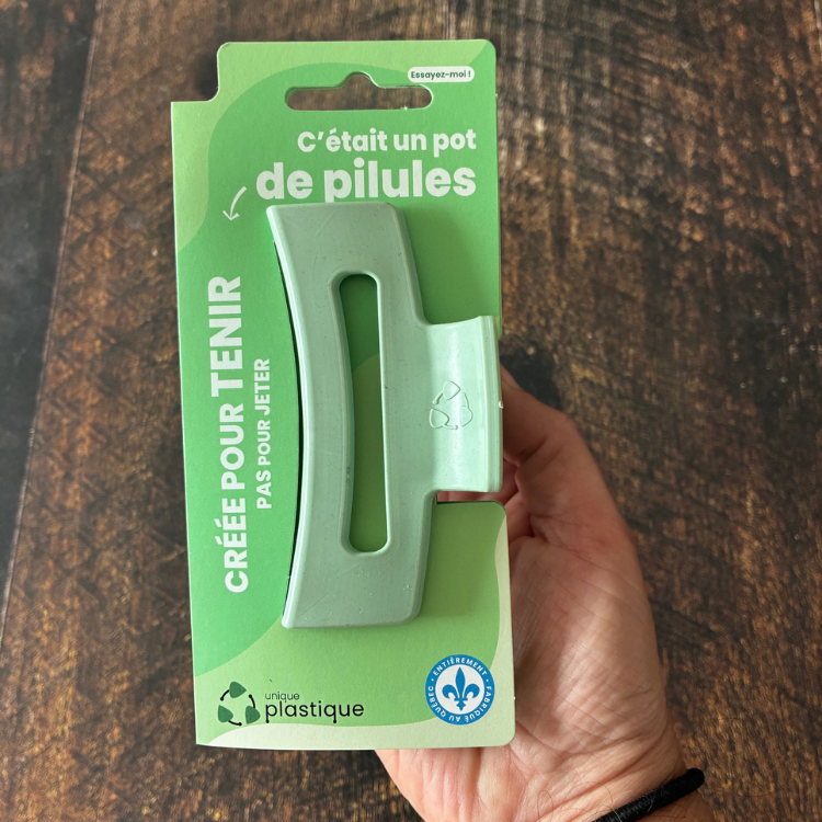 Moyenne pince à cheveux de couleur jade avec un logo de matériau recyclé et son emballage cartonné vert qui dit:  C'était un pot de pilules, créée pour tenir pas pour jeter, Unique plastique et le logo fait au Québec. 