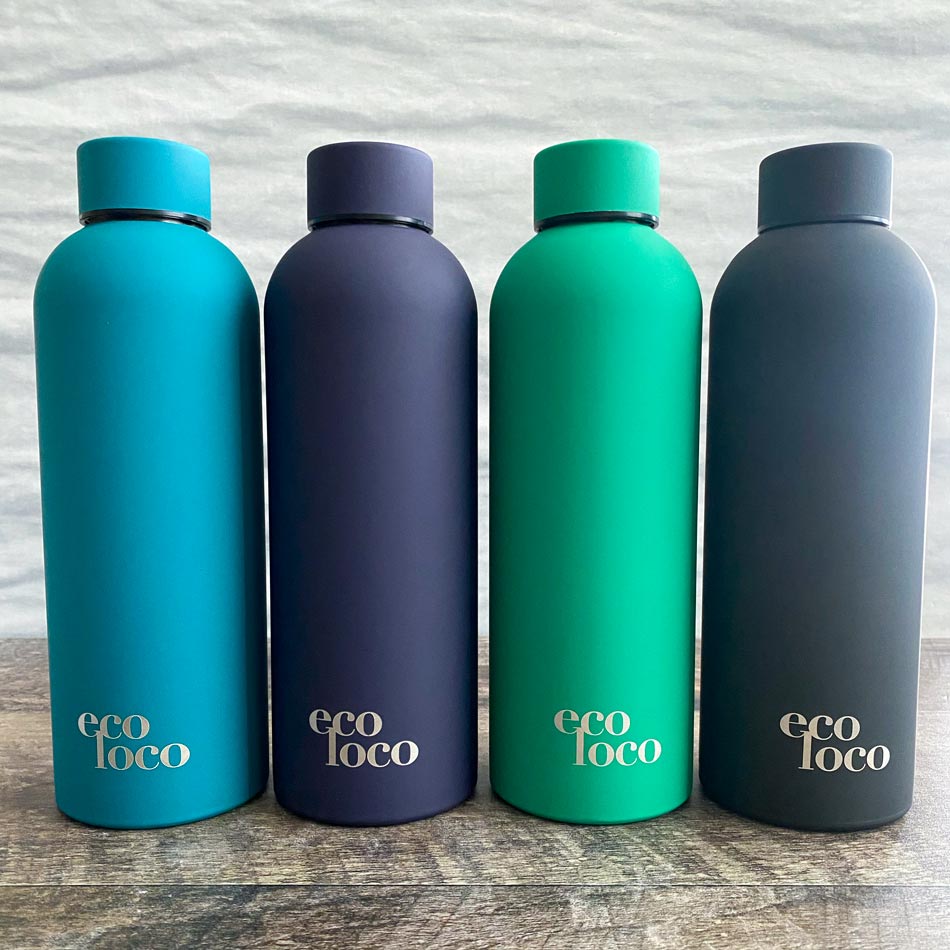 Quatre bouteille d'eau bleue, mauve violet, vert turquoise et voir en acier inoxydable sur un fond de bois 