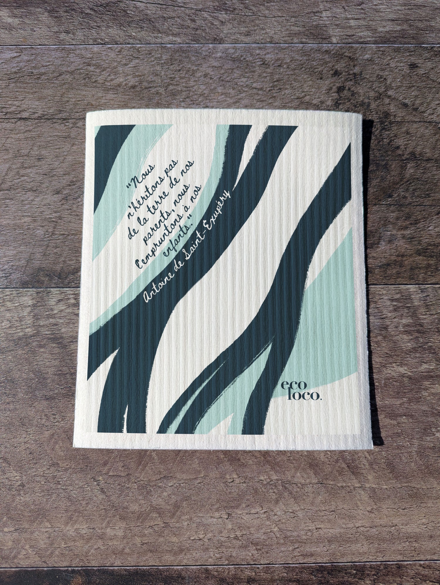 Chiffon suédois ou essuie-tout réutilisable avec un motif de vague et une écriture d'antoine de st-Exupery sur un fond blanc