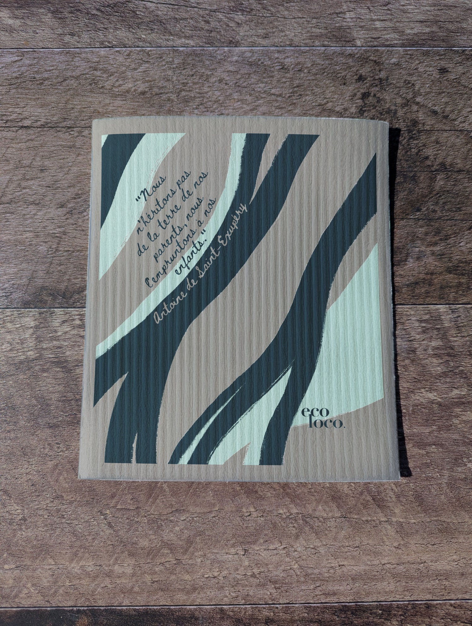 Chiffon suédois ou essuie-tout réutilisable avec un motif de vague et une écriture d'antoine de st-Exupery sur un fond Gris