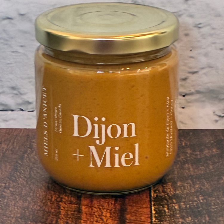 Pot en verre de moutarde de dion au miel du Québec déposé sur une planche en bois.  Miels d'acinet