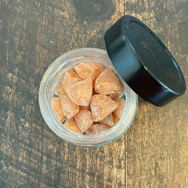 Pot en verre de pastille de propolis et miel des Miels d'Anicet ouvert et déposé sur une planche de bois