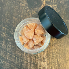 Pot en verre de pastille de propolis et miel des Miels d'Anicet ouvert et déposé sur une planche de bois