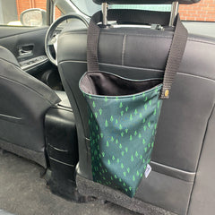 Corbeille poubelle de voiture accrochée sur un banc de cuir noir avec un motif de petites sapins verts